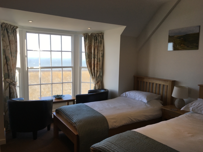 Beds and a seating area in the window of a family room at the Hartland Quay Hotel