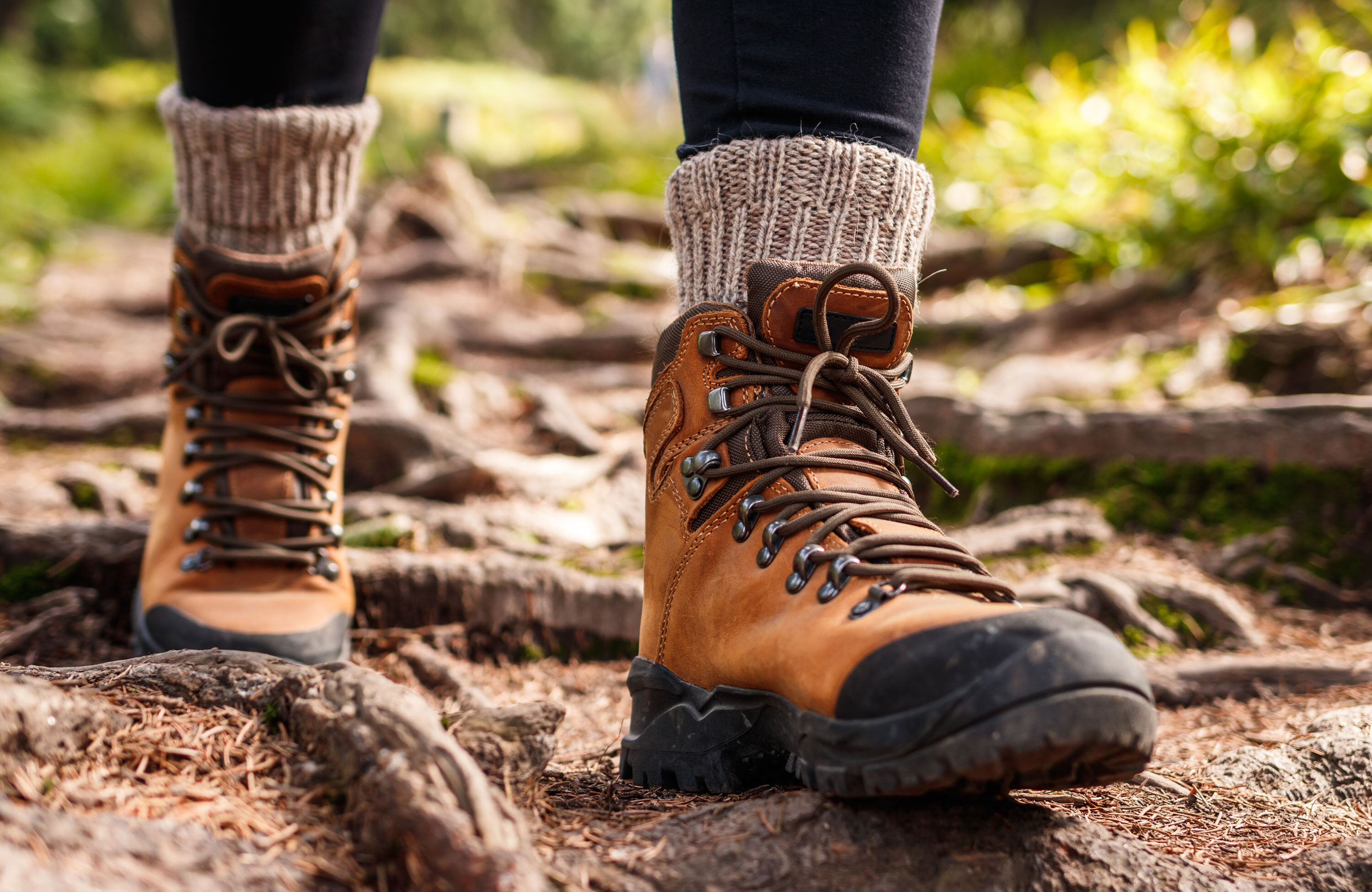 A close up of a woman's walking boots as she hikes over rocky ground
