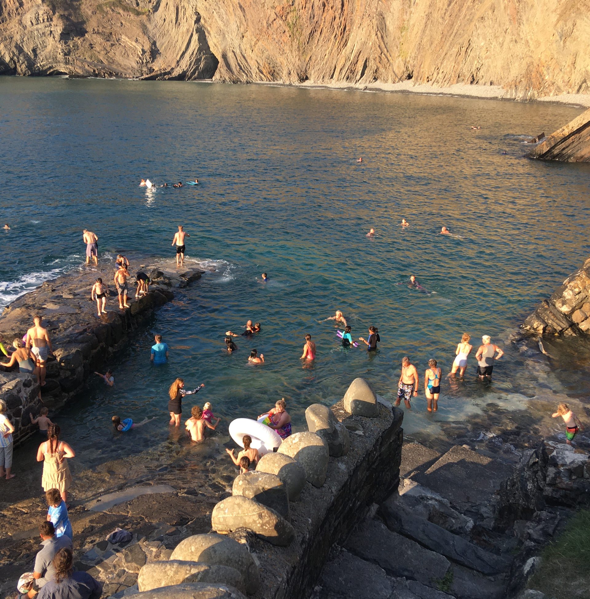 People swimming on shoreline at Hartland Quay on summers day